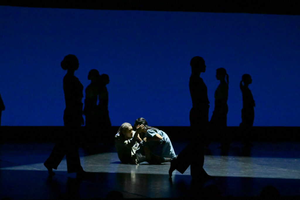 Contemporary dancers performing on stage under blue lighting